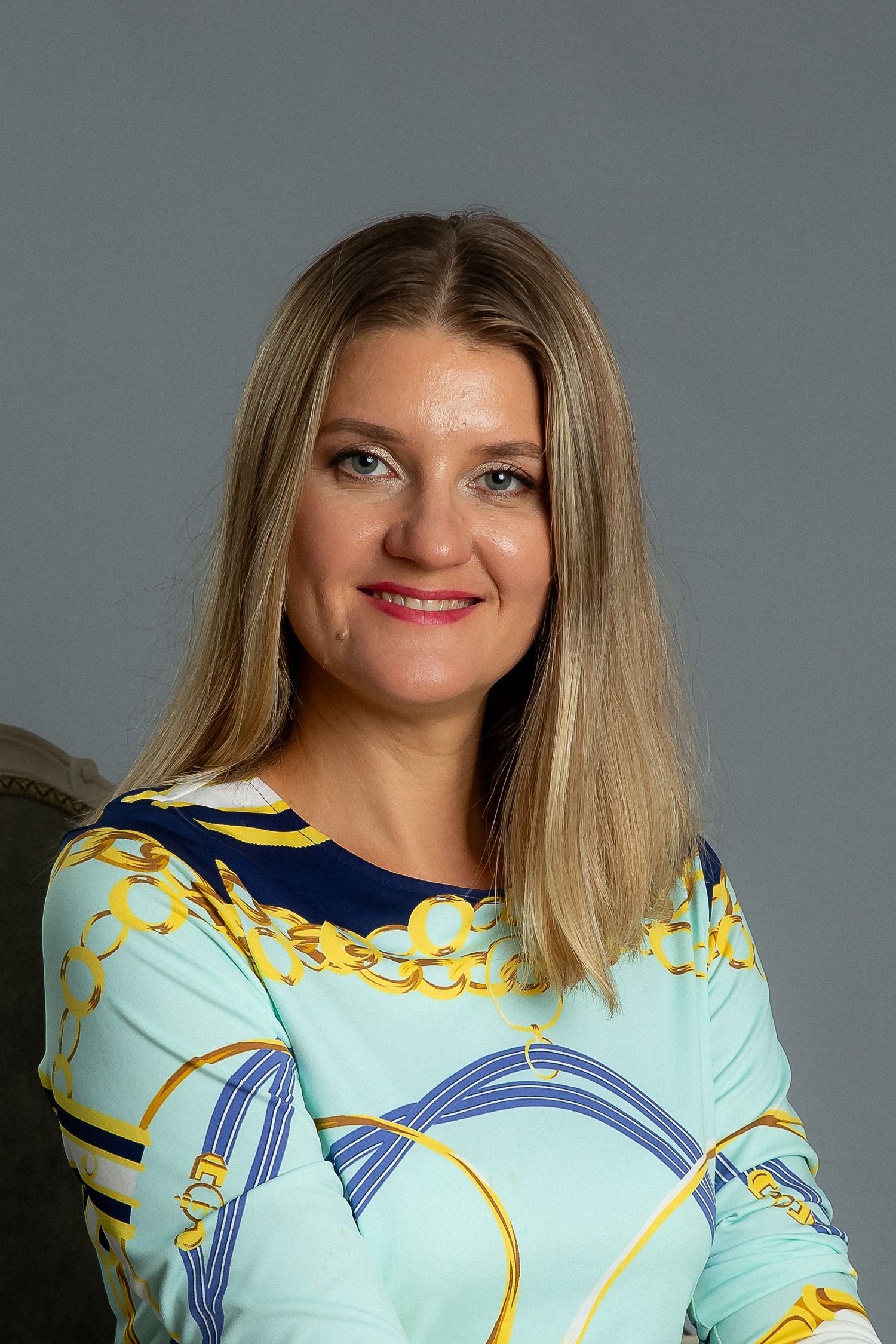 Woman wearing light blue floral print top smiling in professional headshot series.