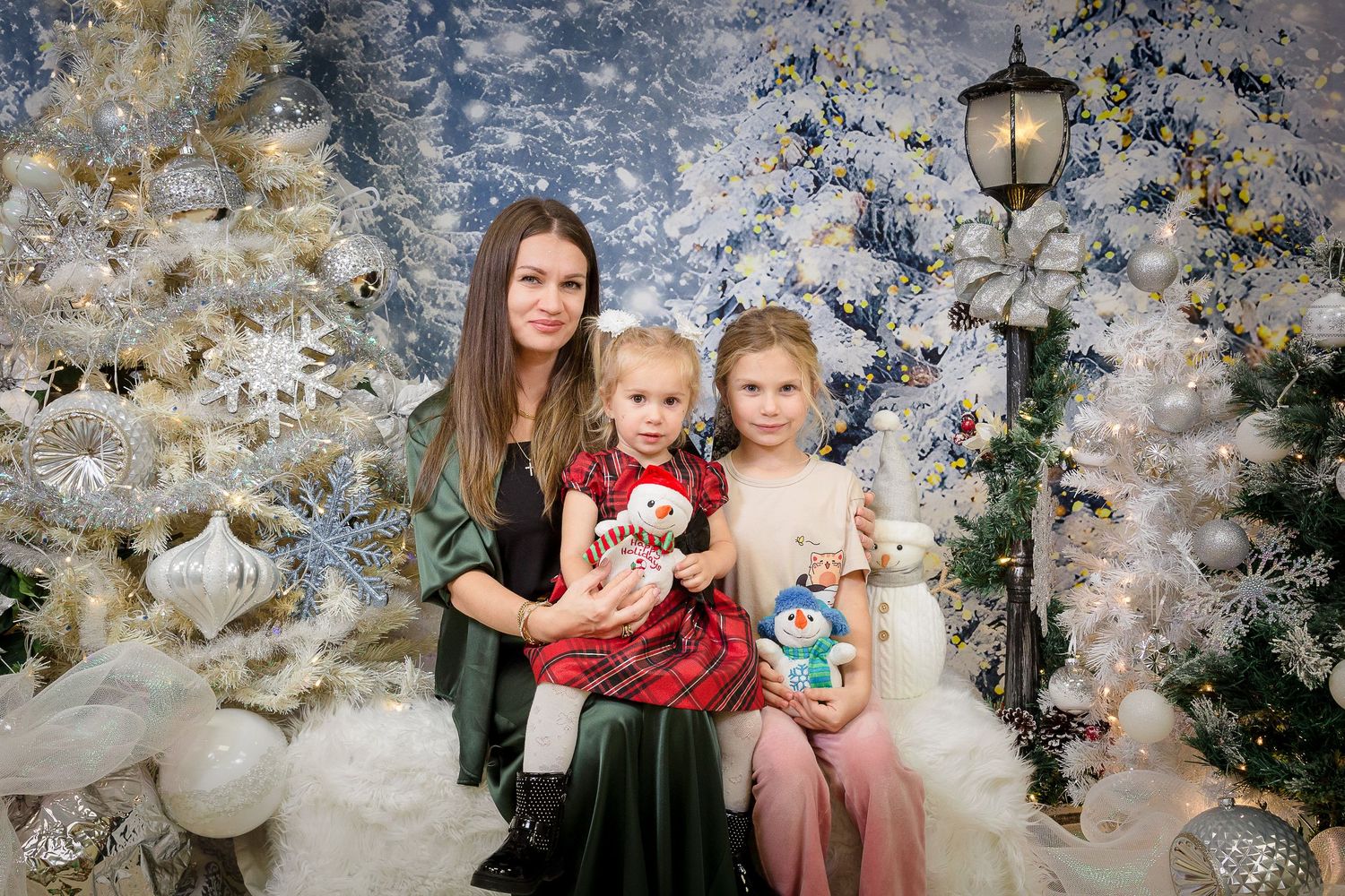 Holiday portrait setup with white fluffy rug, lamp post, and winter decorations against blue backdrop.