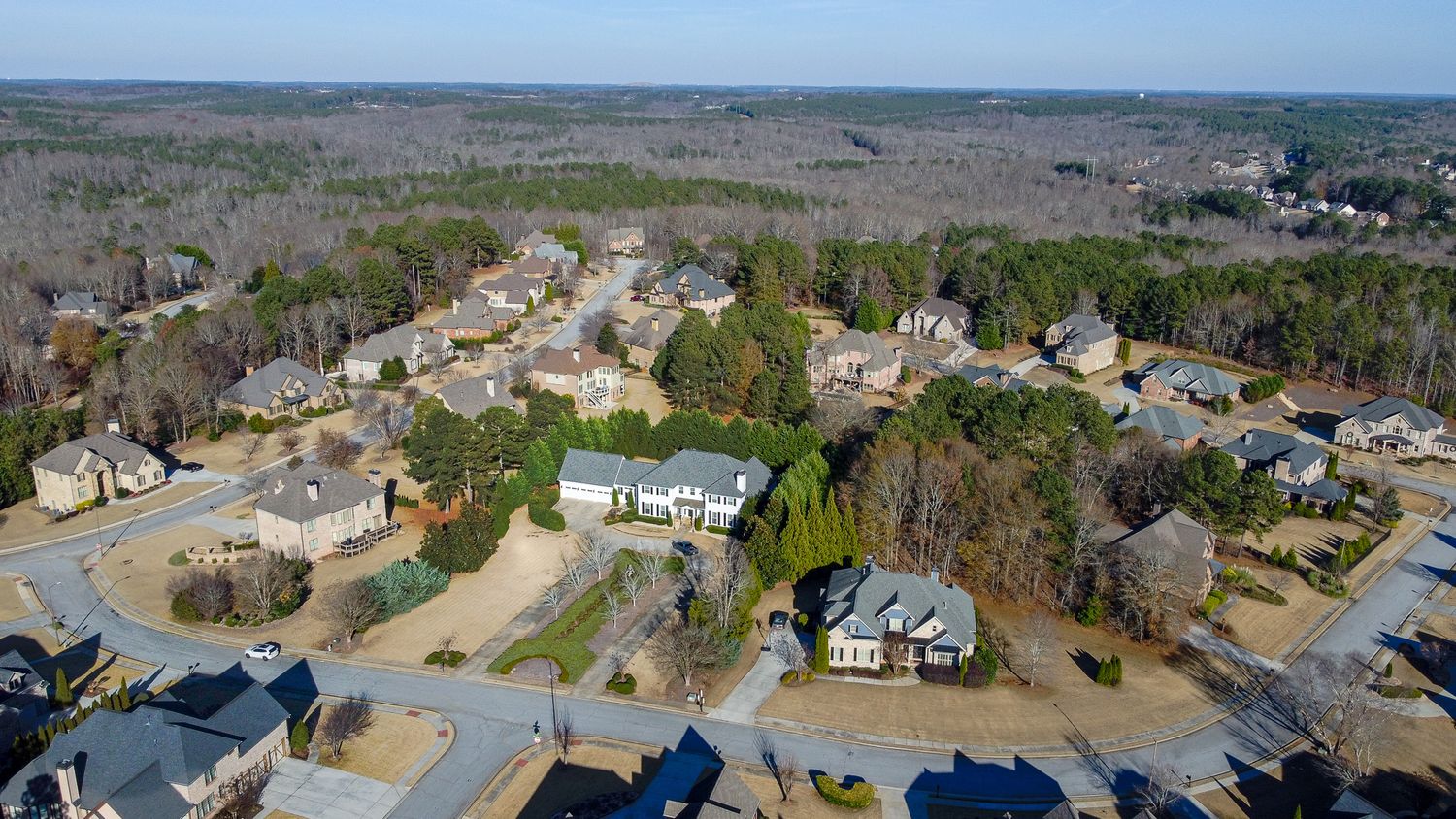 Aerial panoramic view of a residential neighborhood with houses and landscaped yards on a sunny day.
