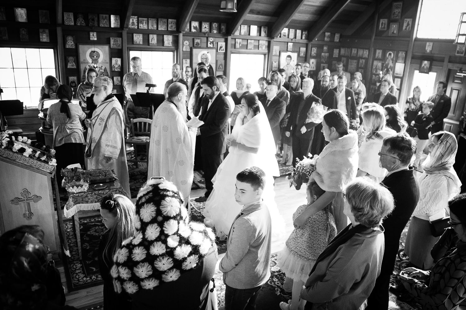 Black and white overhead view of a wedding ceremony with guests gathered in a decorated church.
