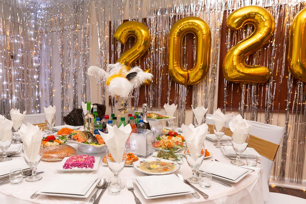 Elegant party setup with silver tinsel backdrop and formal place settings.