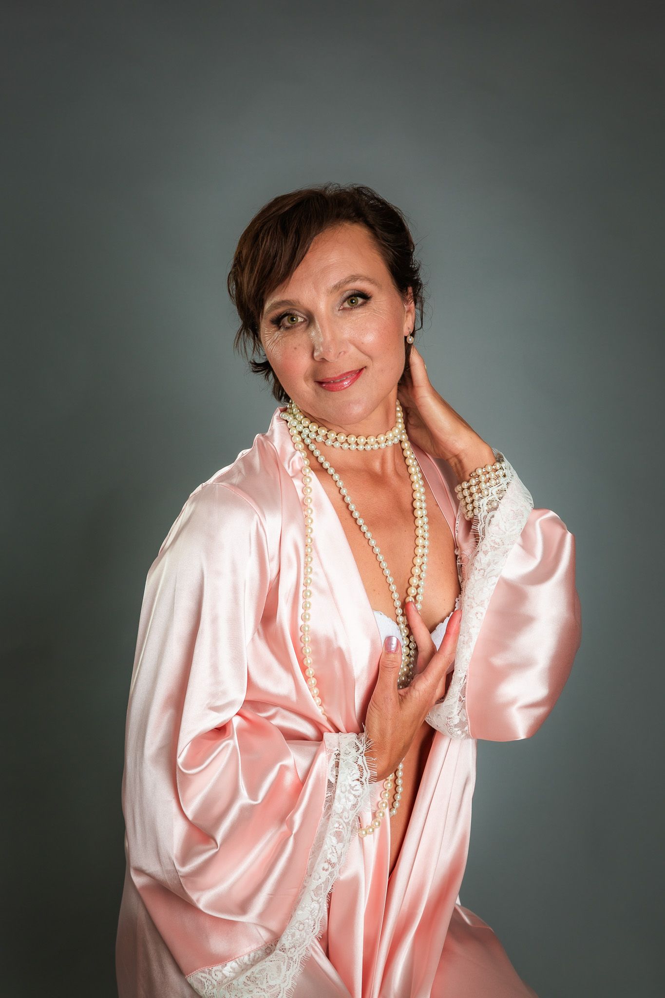Intimate boudoir portraits featuring pink silk robe and pearl necklace against dark background.