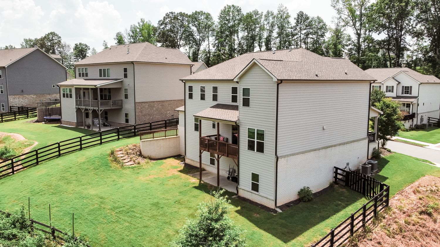 Aerial shot showing multiple residential properties with fenced yards and green landscaping.