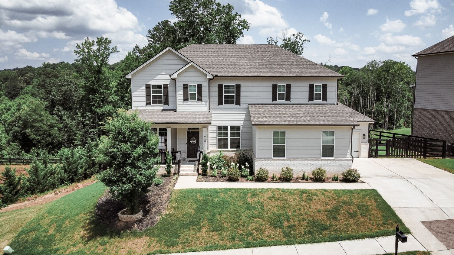 Aerial view of a modern two-story white suburban house with landscaped yard and driveway.