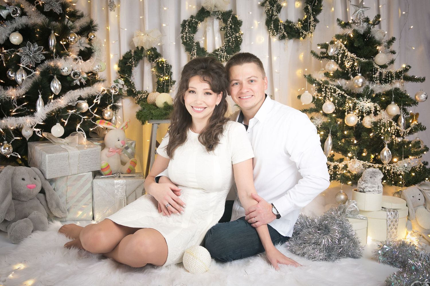 Holiday photo session with decorated Christmas trees and white lights in the background.