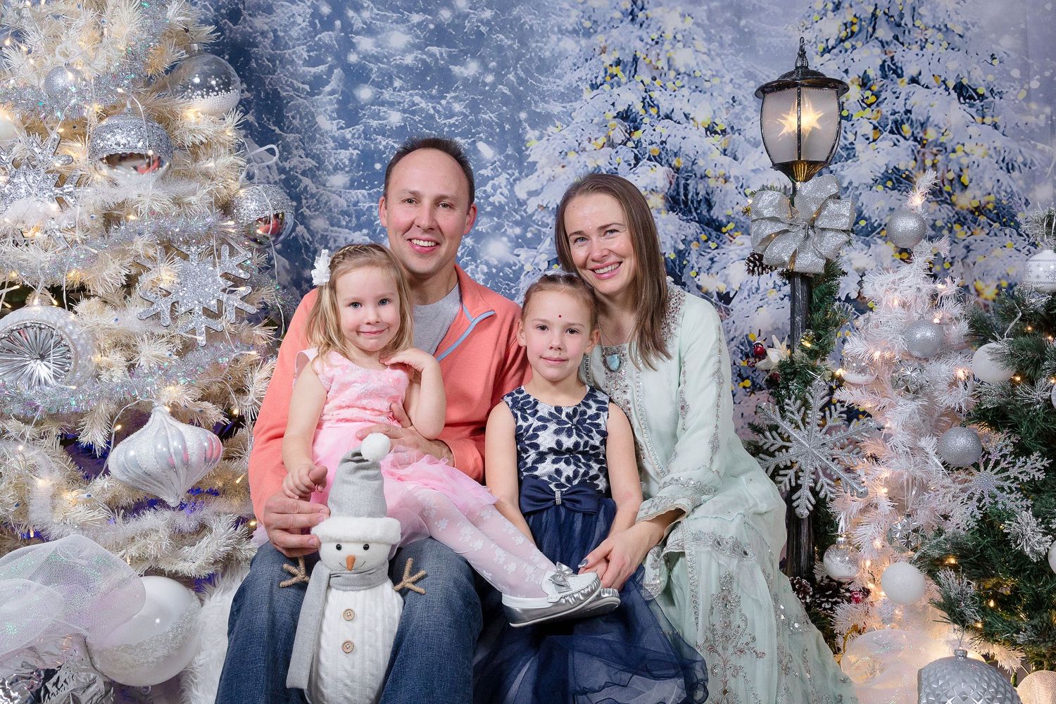 Holiday family portraits with flocked Christmas trees and coordinated winter outfits.