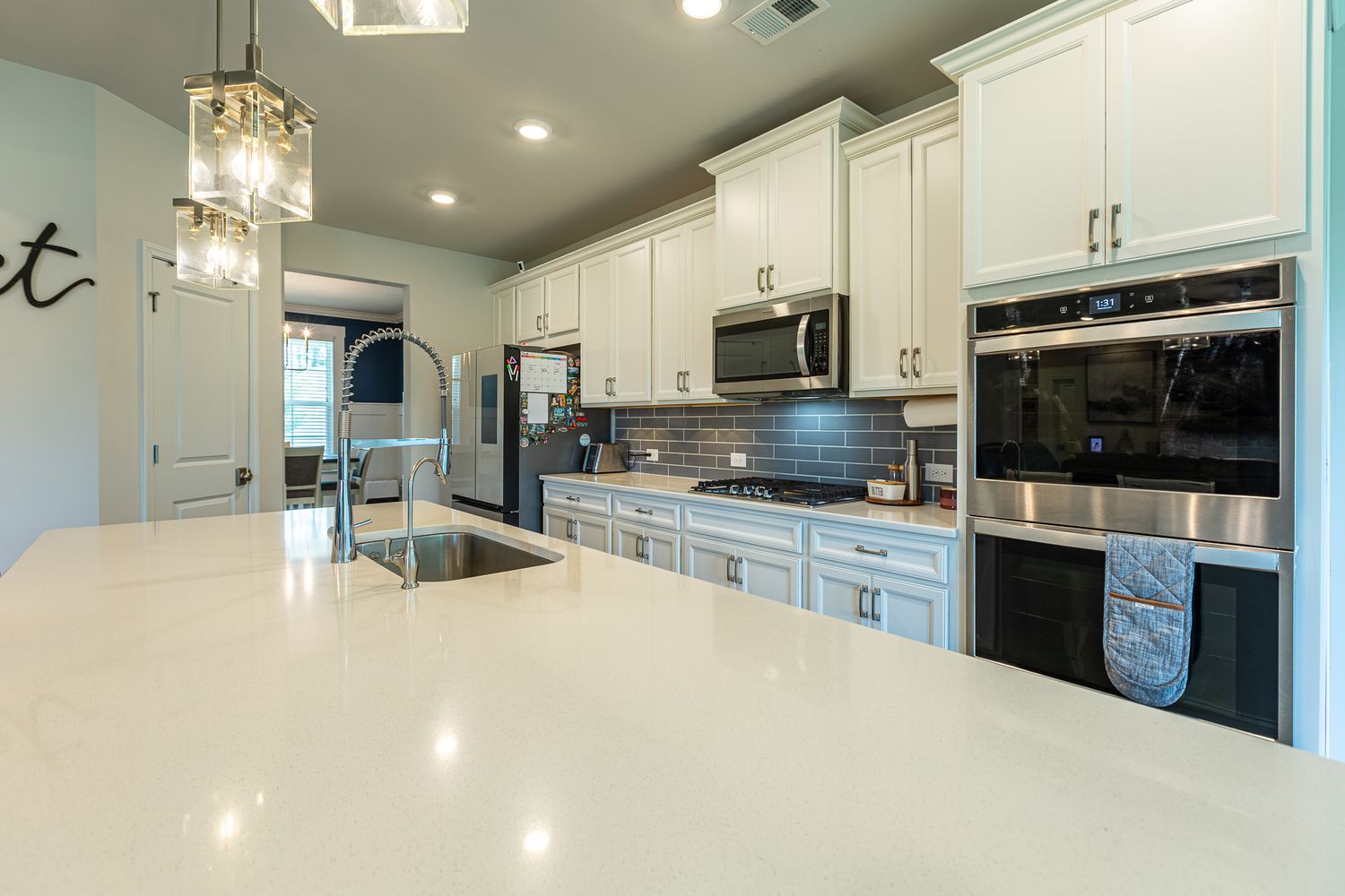 Sleek modern kitchen with white cabinets, stainless appliances, and pendant lighting.
