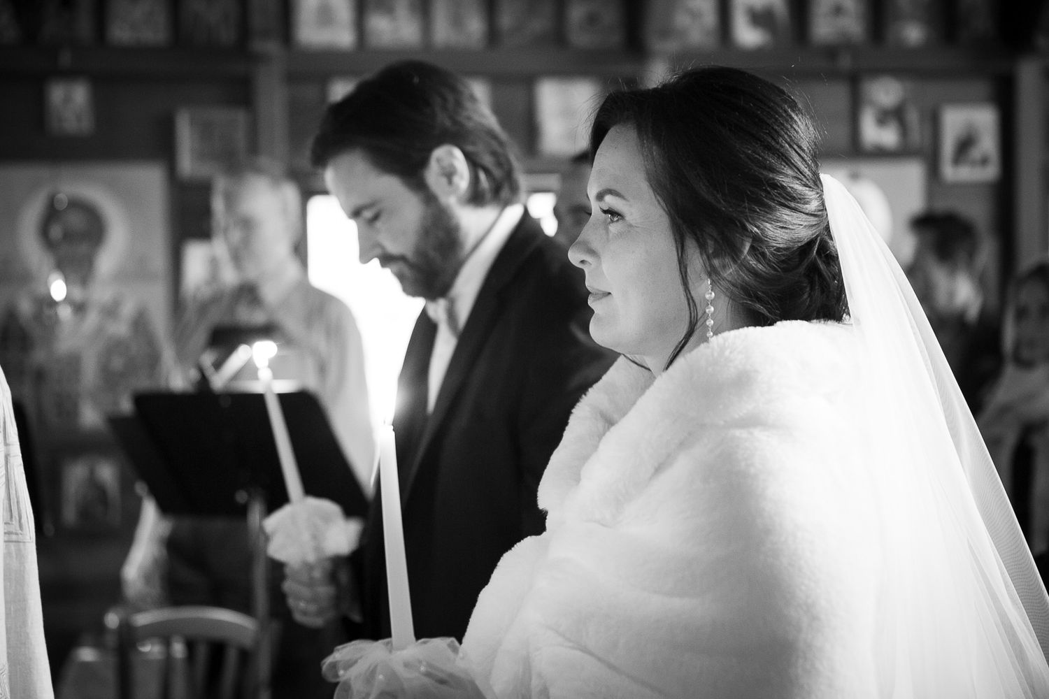 Black and white photo of a bride and groom holding candles during a traditional church wedding ceremony.