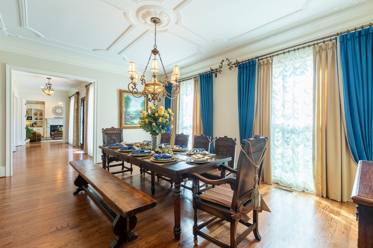 Bright formal dining area with crown molding, crystal chandelier and teal drapes.