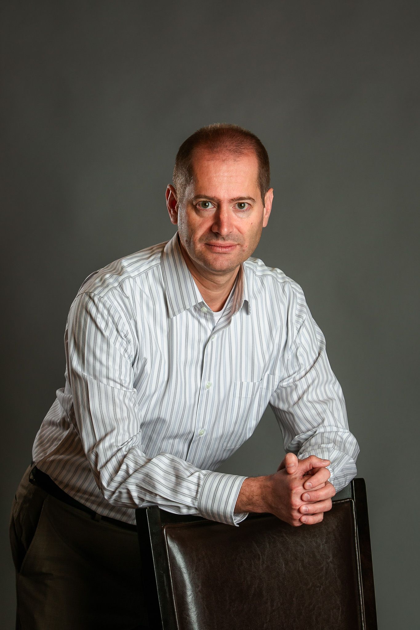 Professional headshot series of man in striped shirt against dark background.