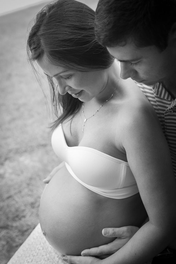 Black and white maternity photos showing couple embracing and cradling pregnant belly.
