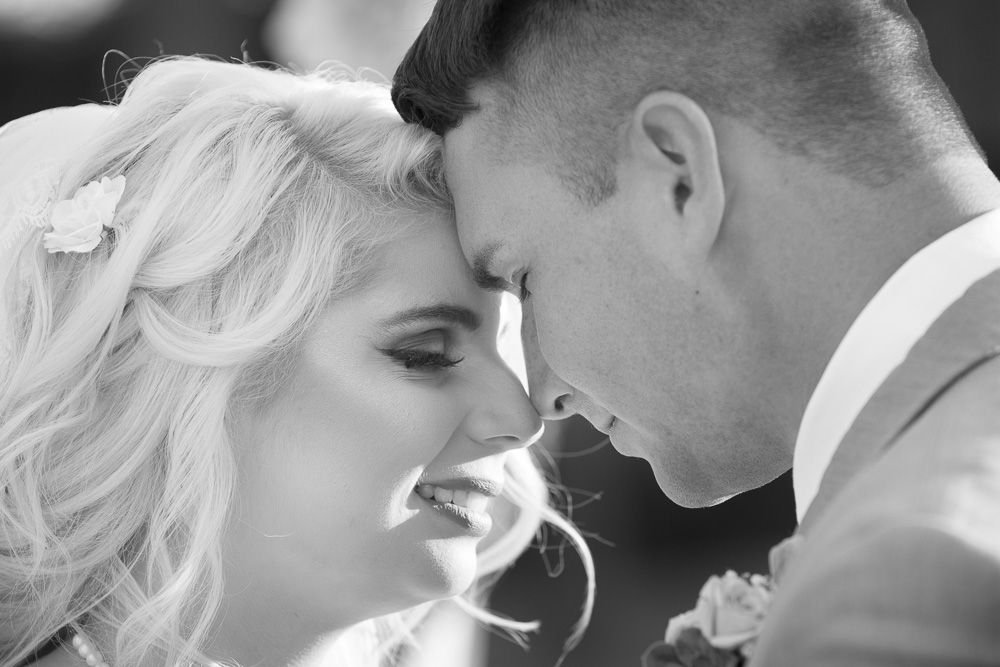 Black and white close-up of bride and groom touching foreheads tenderly on their wedding day.
