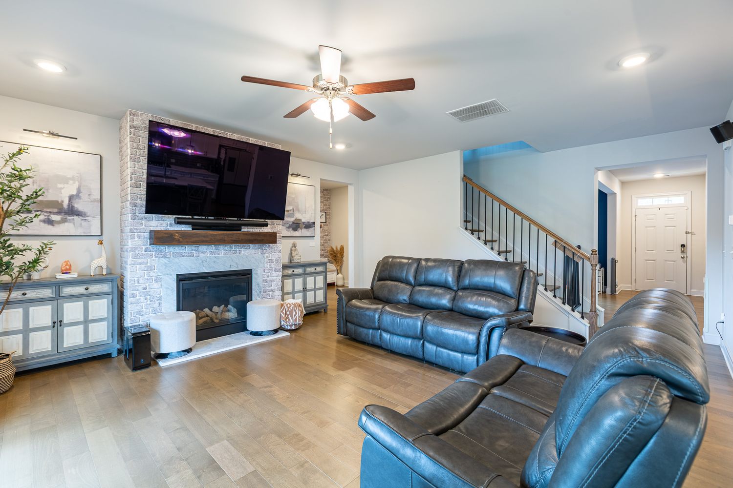 Open concept living room featuring blue leather furniture and mounted television.