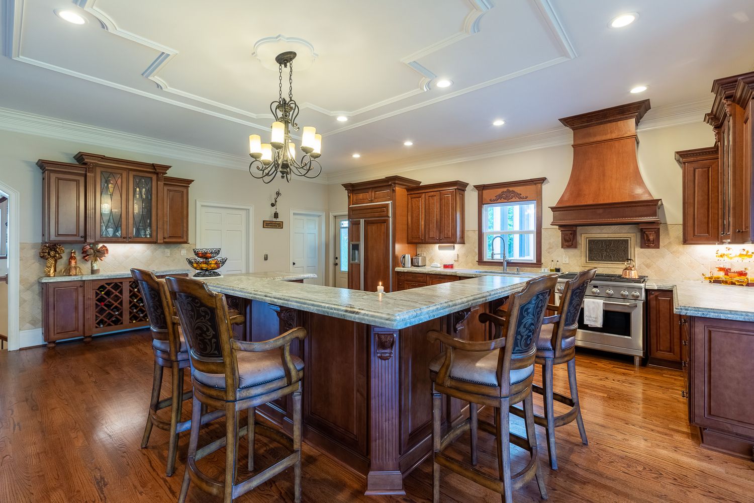 Gourmet kitchen featuring custom cabinetry, copper range hood and breakfast bar.