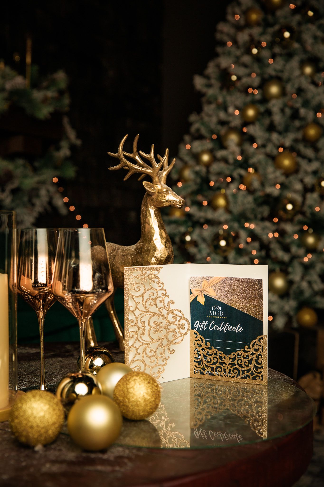 Elegant holiday setup with gold deer figurines, ornaments and invitation cards near Christmas tree.