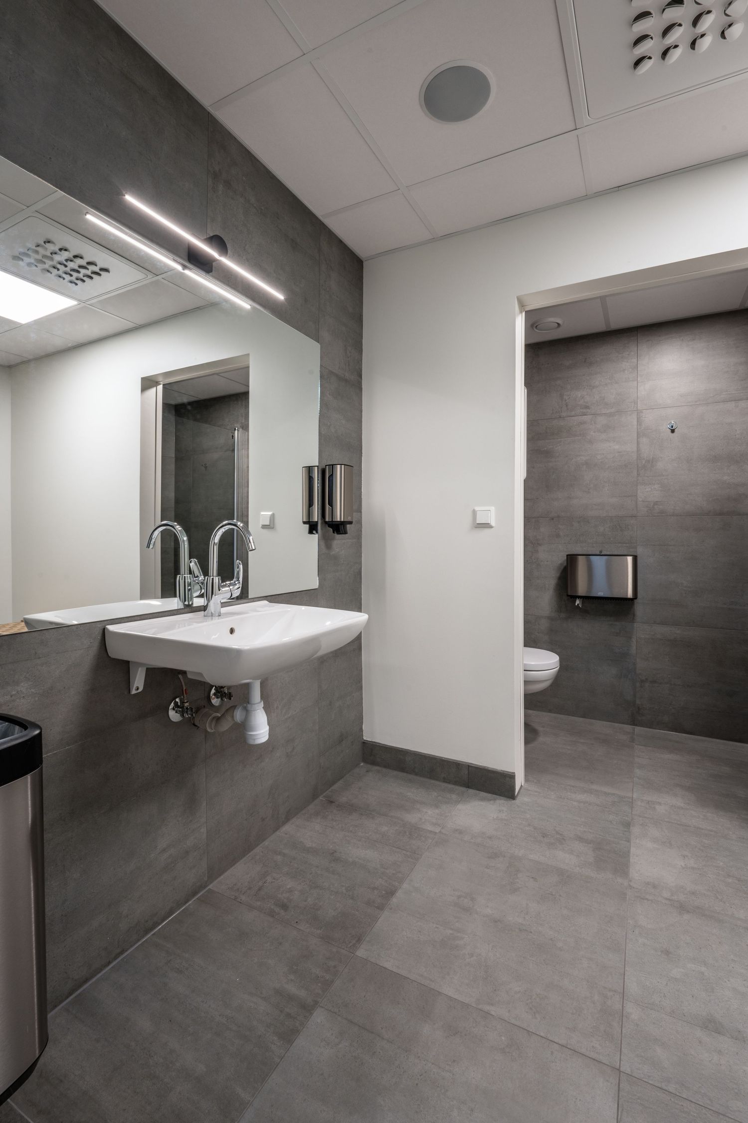 Modern bathroom interior with gray tile walls, white sink and minimalist design elements.