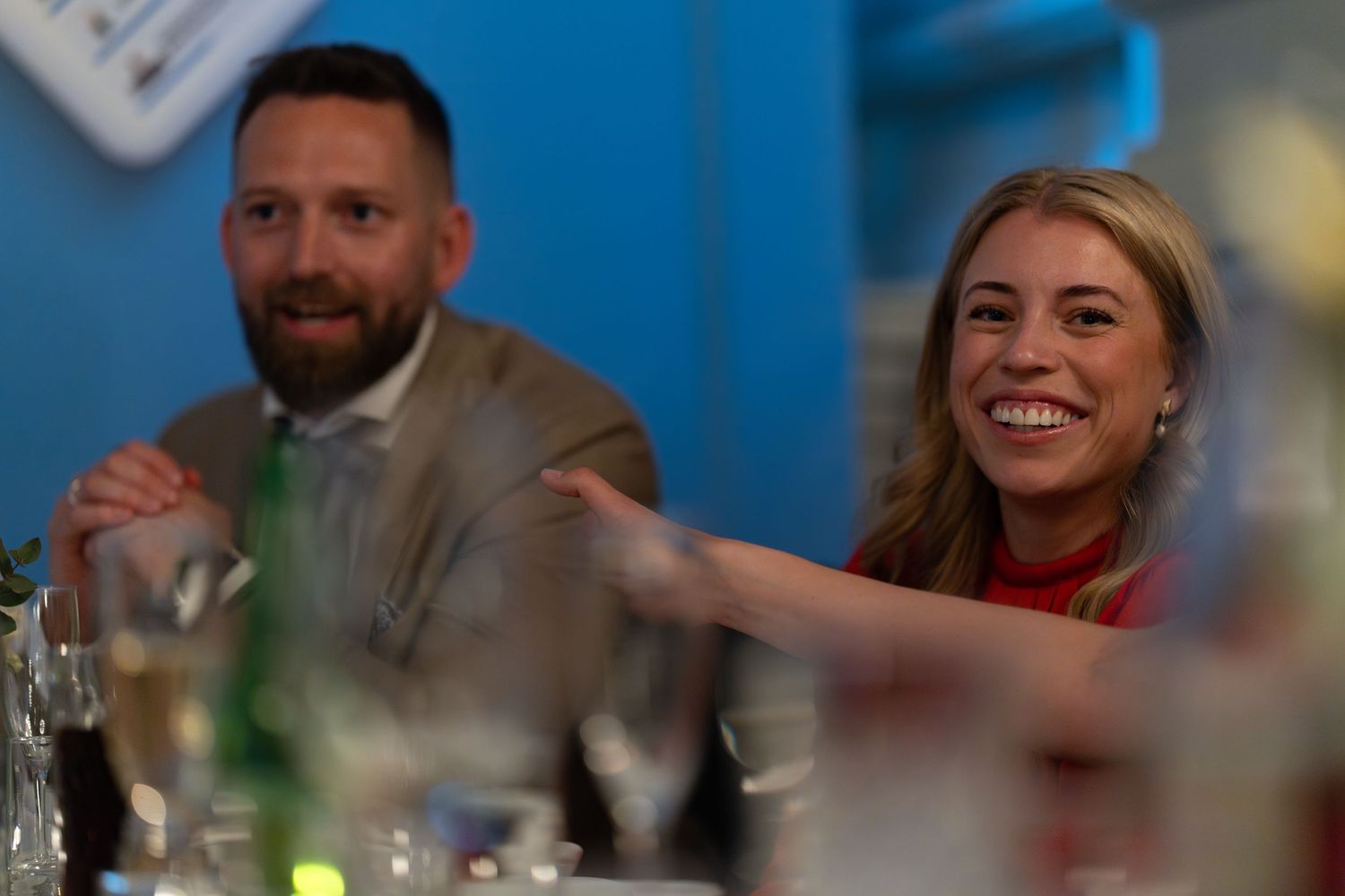 Event attendees engaged in lively conversation at dining table with blue backdrop.