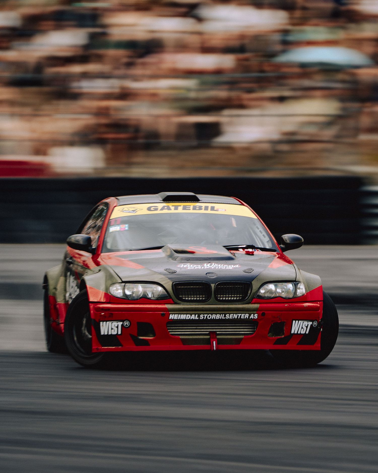 Red race car drifting on track with motion blur showing high speed motorsport action.