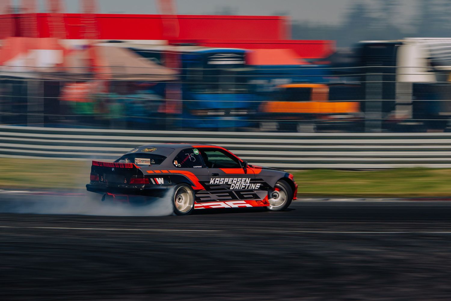 Red and black drift cars slide through turns on a race track during a competitive drifting competition.
