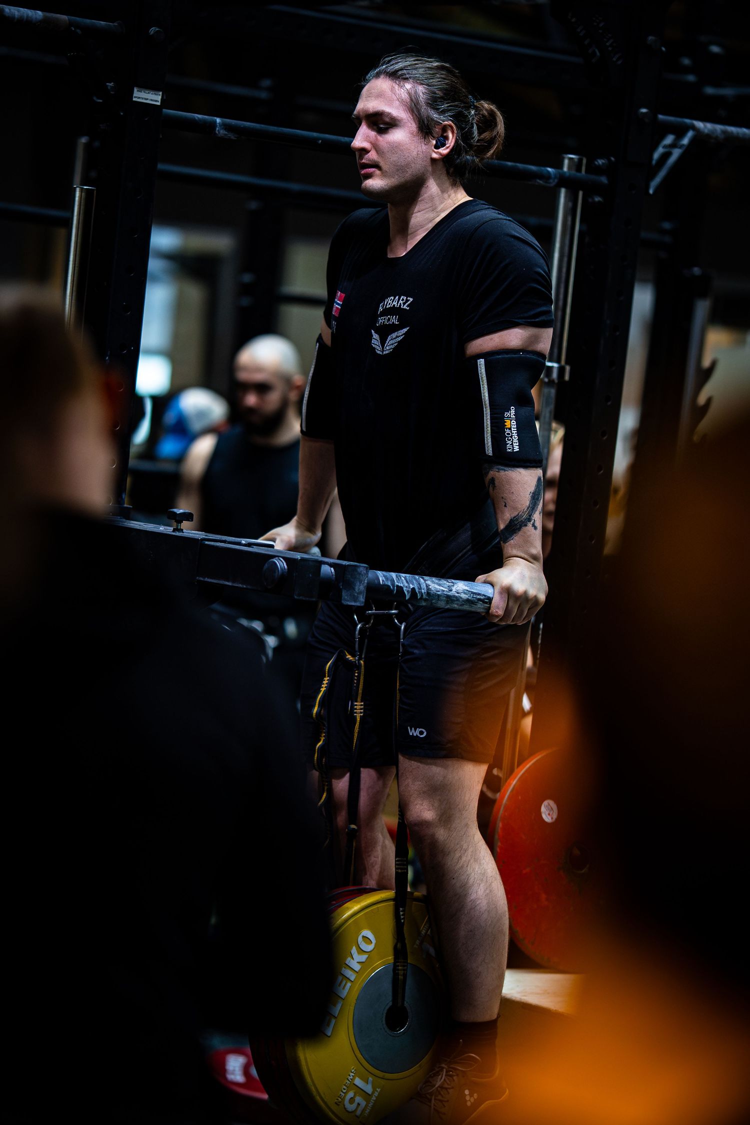 Athlete performing dips on parallel bars in a dark gym wearing black workout attire.
