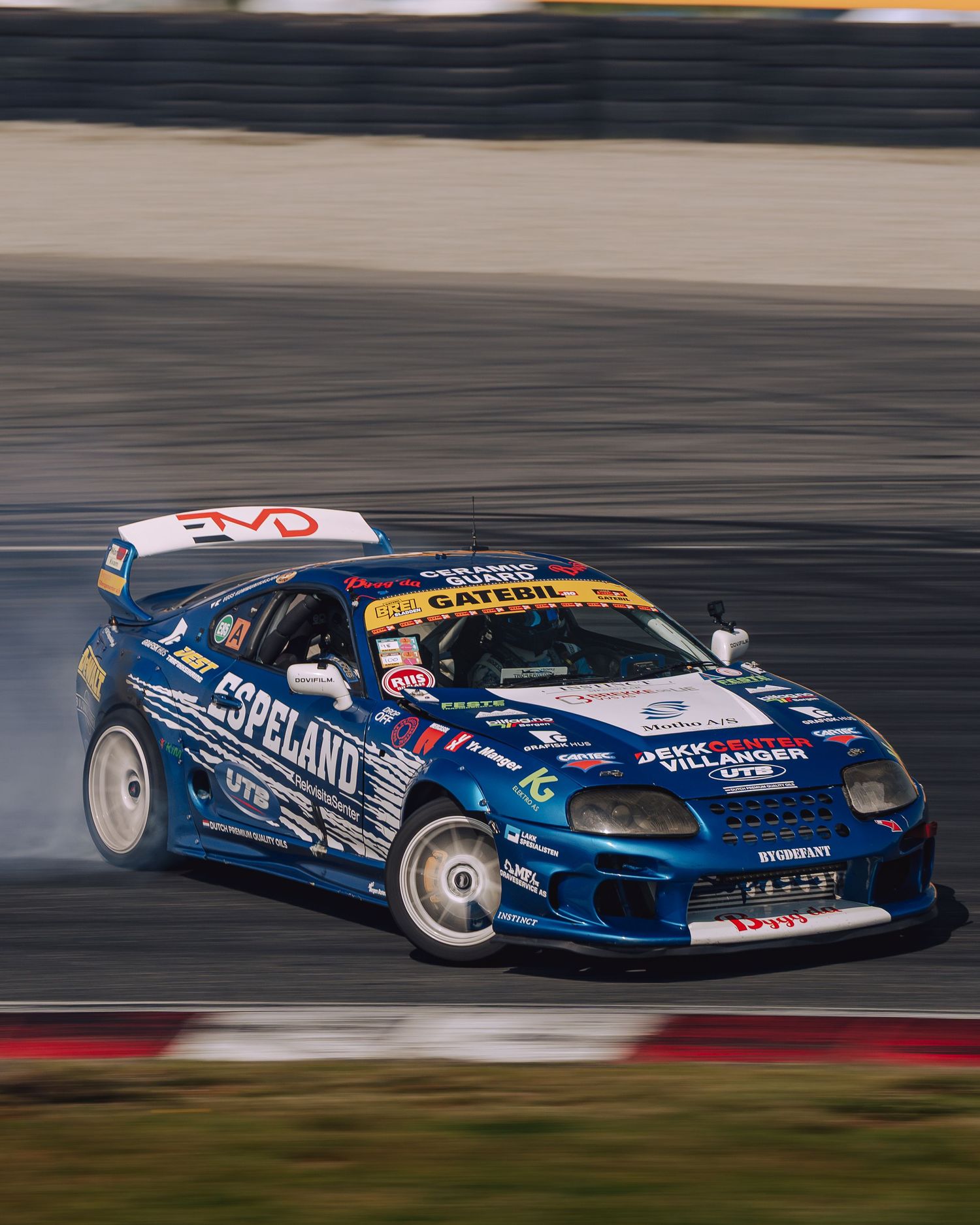A blue racing car in motion on a racetrack with motion blur effects showing its speed and dynamic movement.