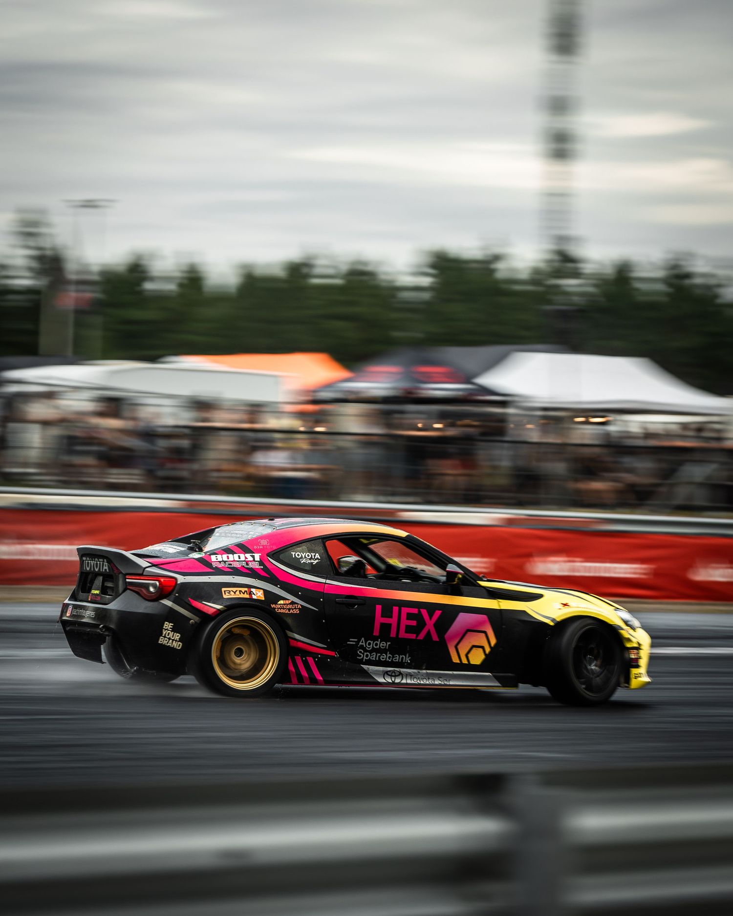 Two racing cars in motion blur compete side by side on a drag strip during a high-speed competition.