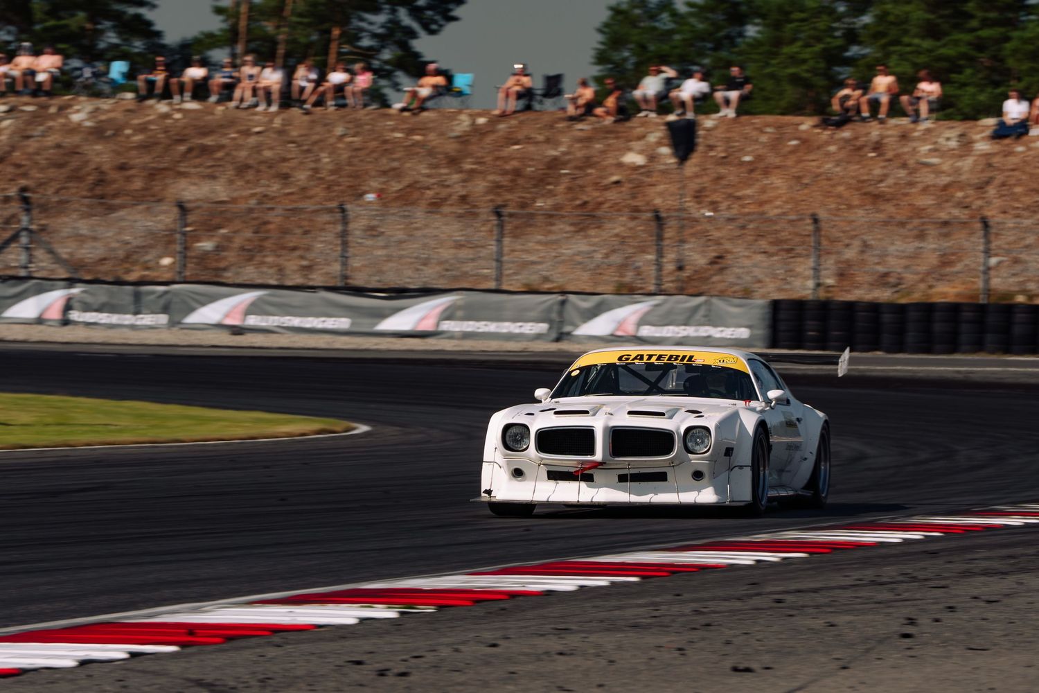 Race cars speed around a track during a competitive motorsport event at a professional racing circuit.
