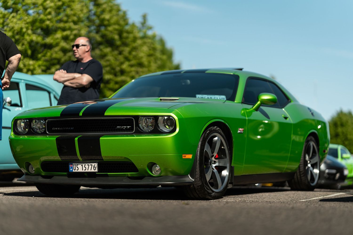 Bright green muscle car with black racing stripes captured in sunlight.