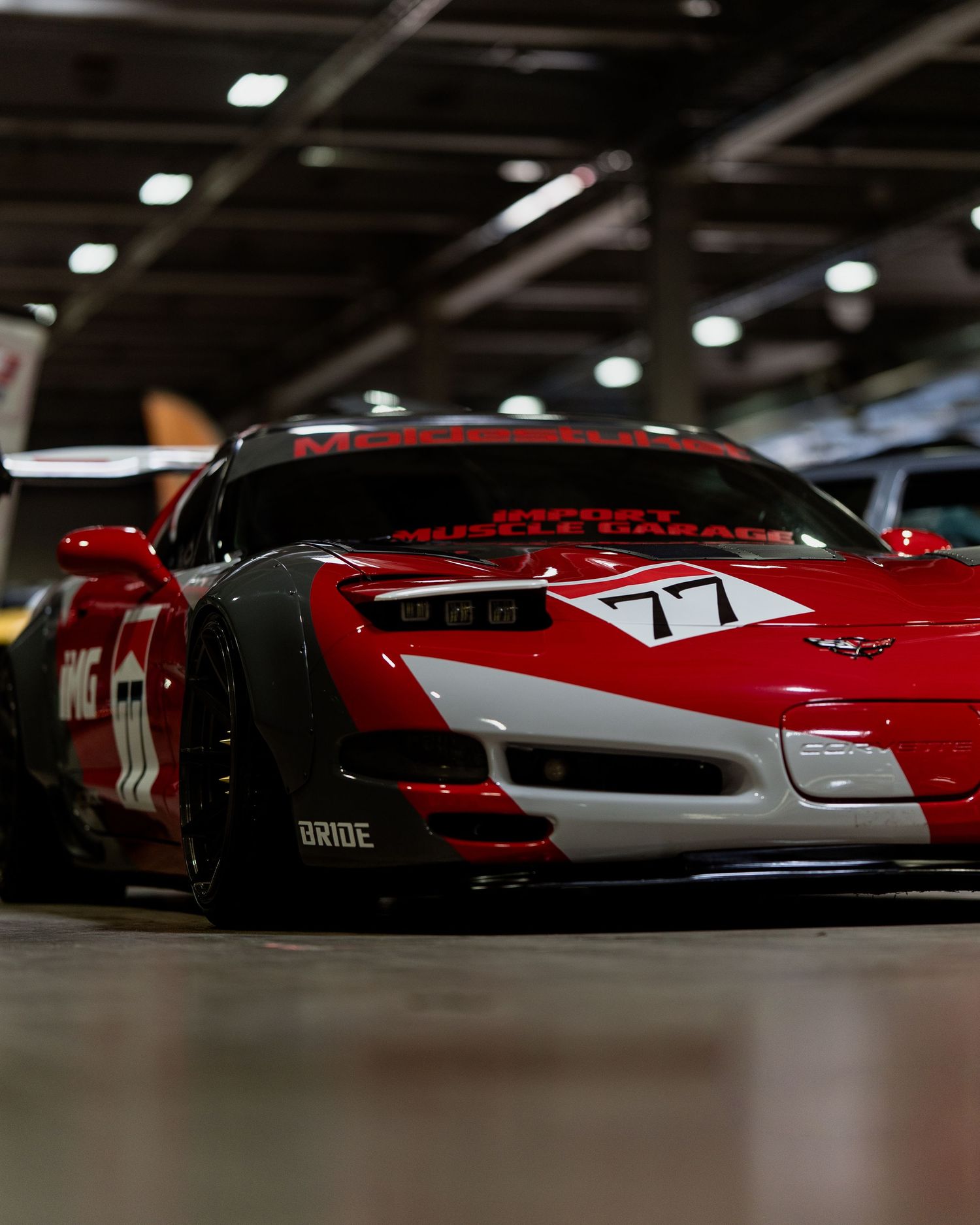 Row of red sports cars photographed from low angle in indoor lighting conditions.
