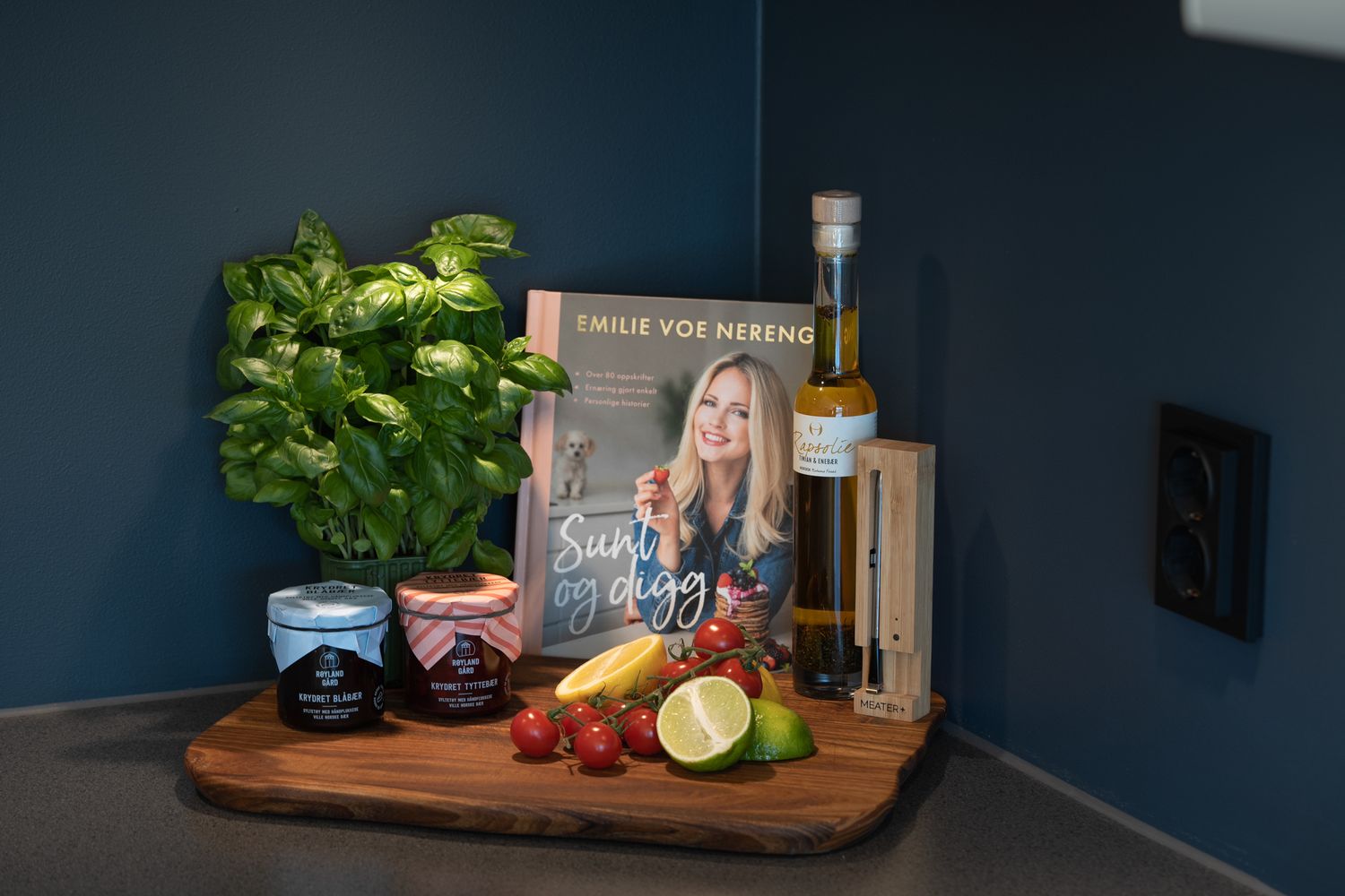 Modern kitchen counter with dark blue walls and wooden cutting board displaying cooking ingredients.