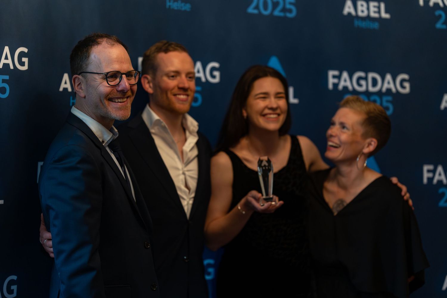 Group celebrating with an award trophy at a formal event with branded backdrop.