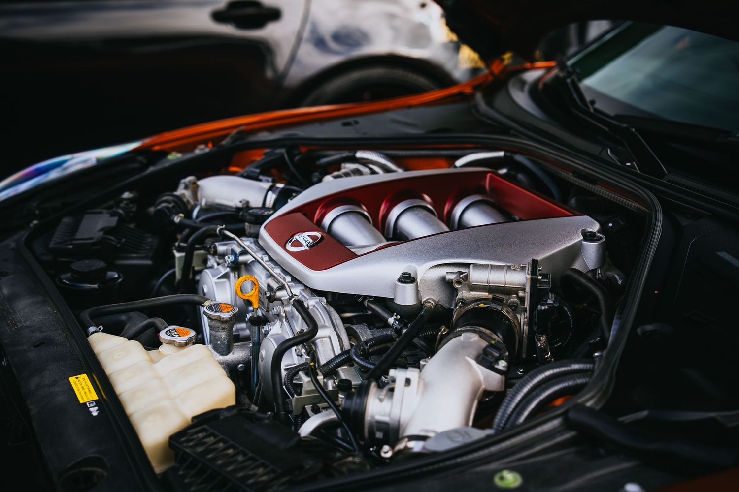 Close up of a high-performance car engine with red intake manifold and silver components.