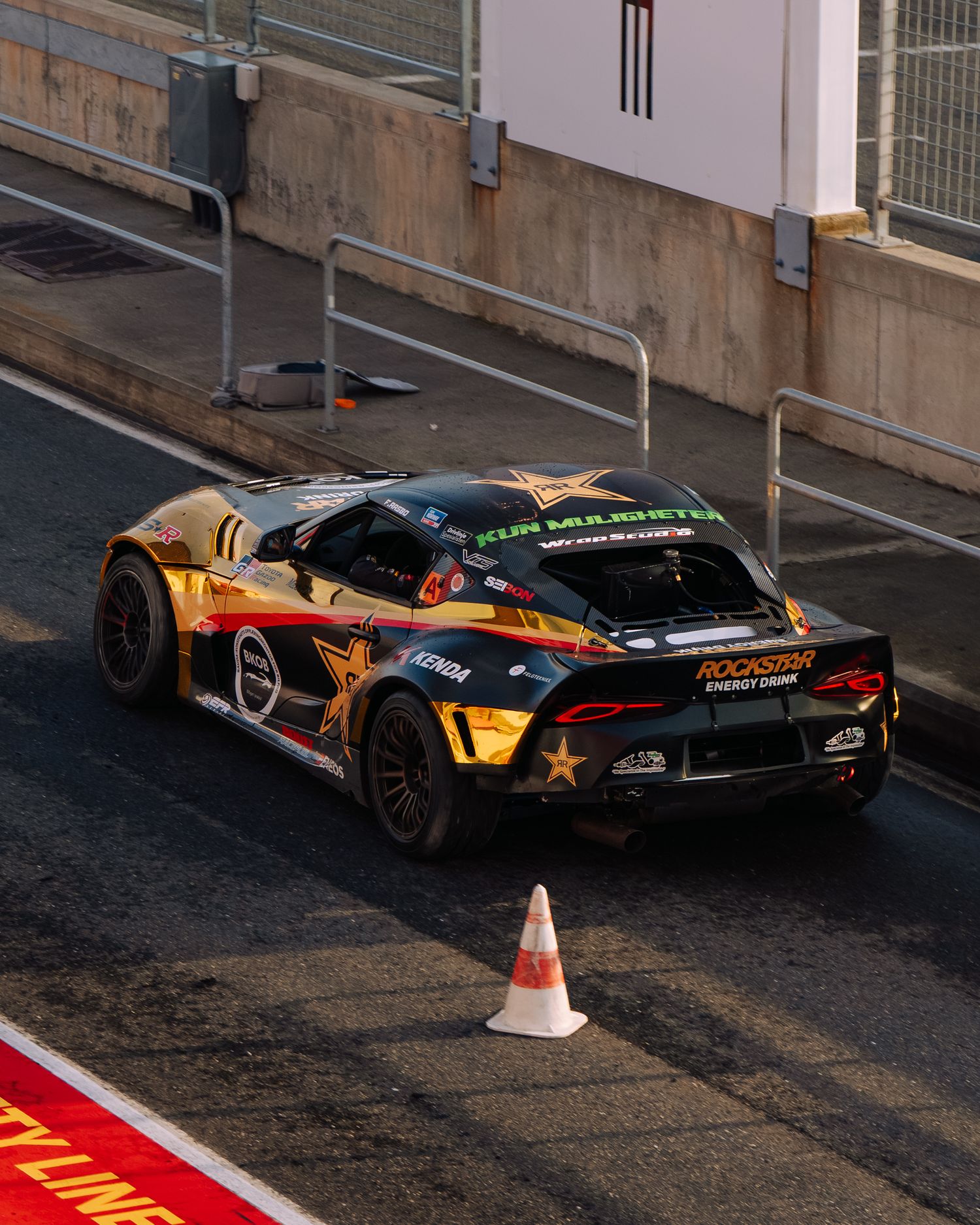 Racing car with yellow and black livery navigates a tight corner on an urban street circuit during a motorsport event.