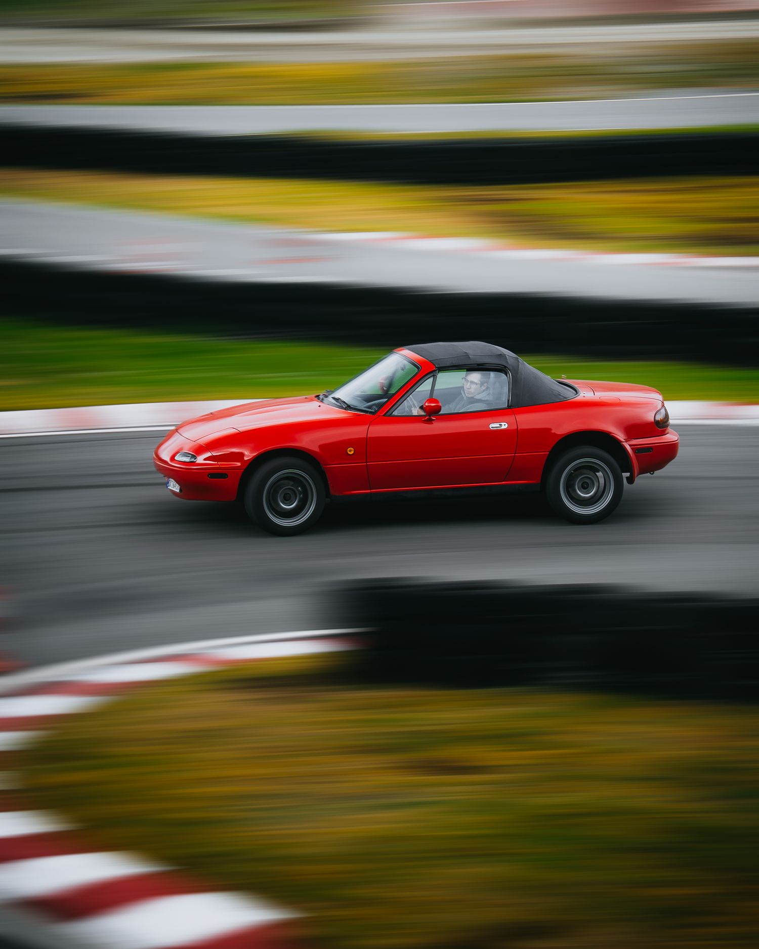 A red sports car in motion on a racetrack with motion blur effects creating a dynamic sense of speed.