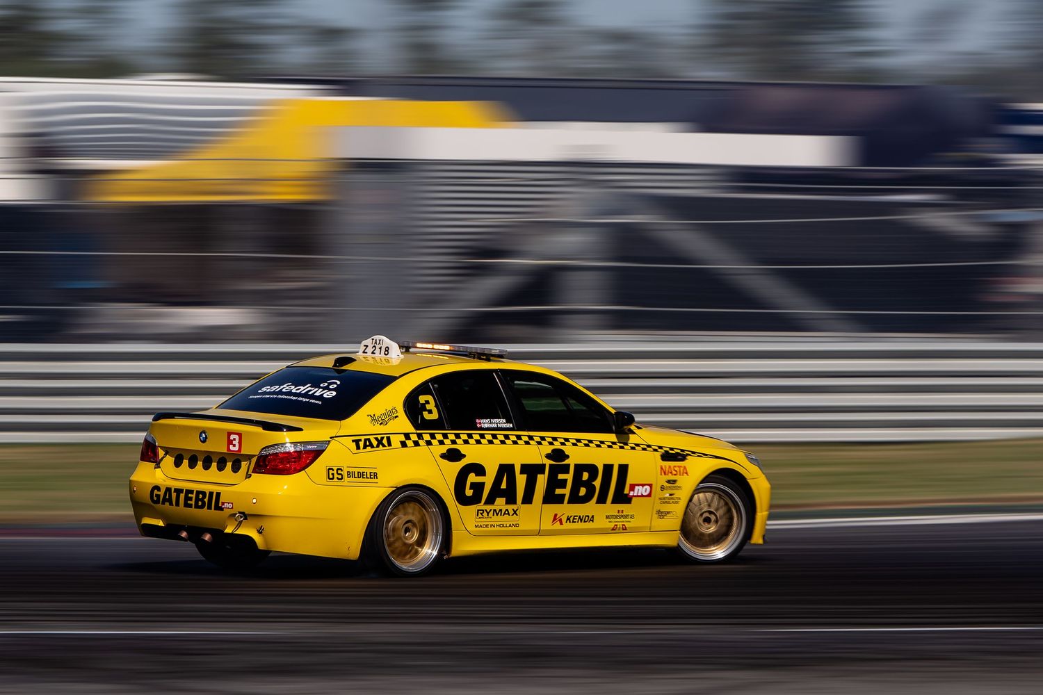 Yellow racing car speeds down racetrack with motion blur effect creating dynamic action shot.