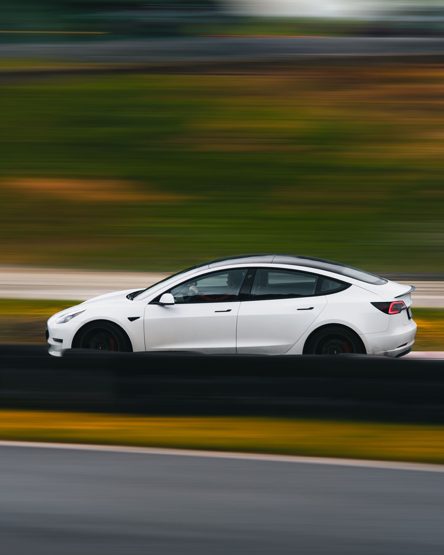 A white sports car in motion captured with motion blur effect on a racetrack.