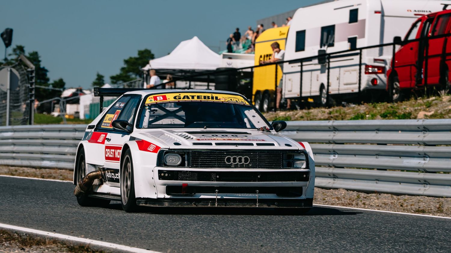 Race cars line up on a track during a motorsport competition, showcasing various high-performance vehicles.