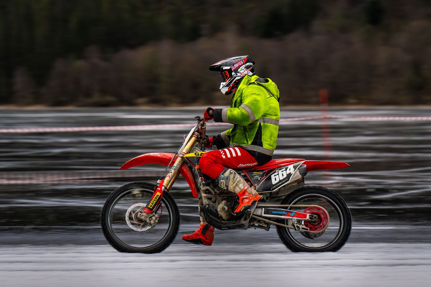 A sequence of action shots showing a motocross bike performing a jump sequence on a wet surface.