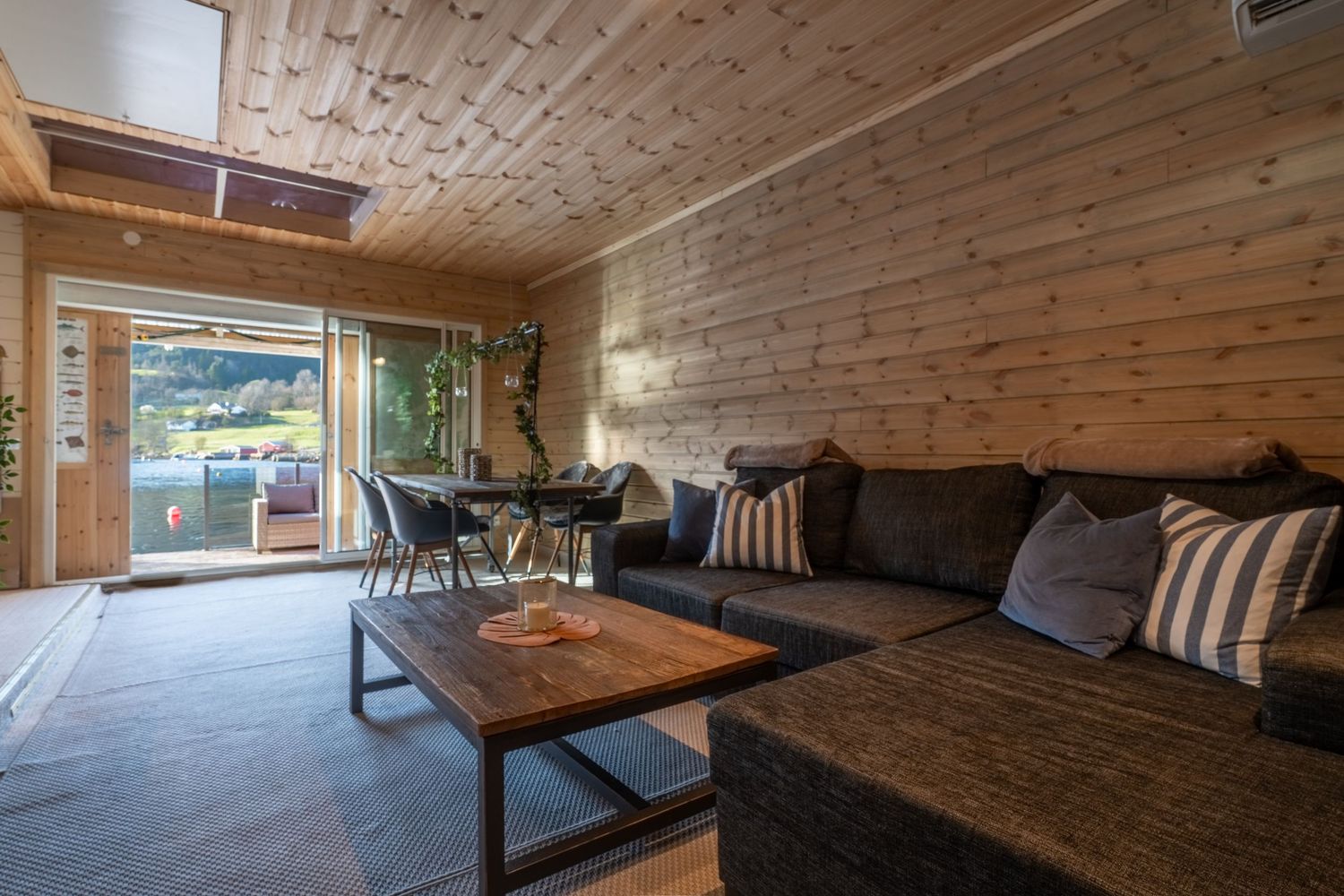 Open-concept living space with wood ceiling, large sectional sofa, and sliding glass doors.