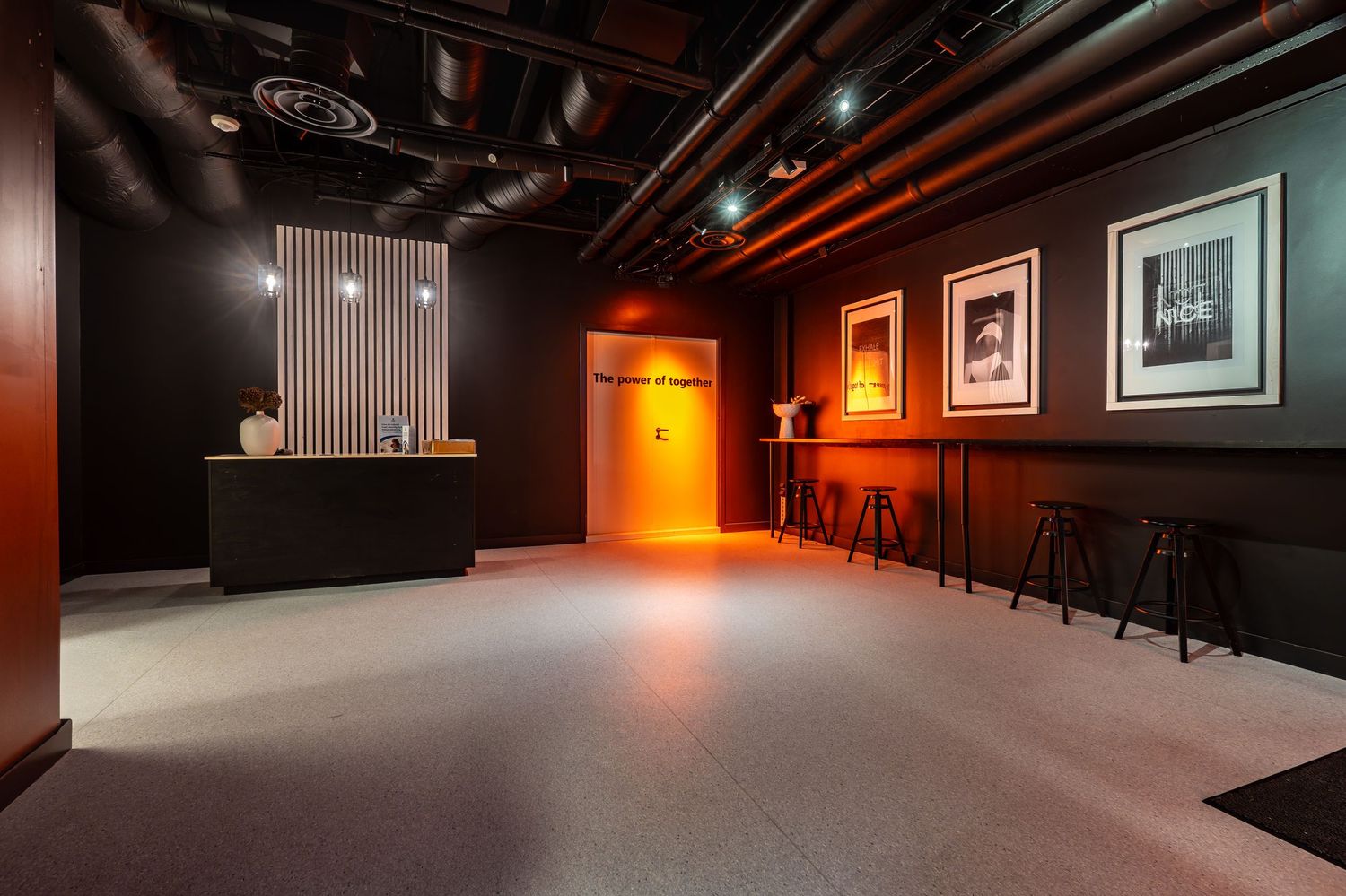 Modern reception area with dark walls, orange accent lighting, and bar seating.