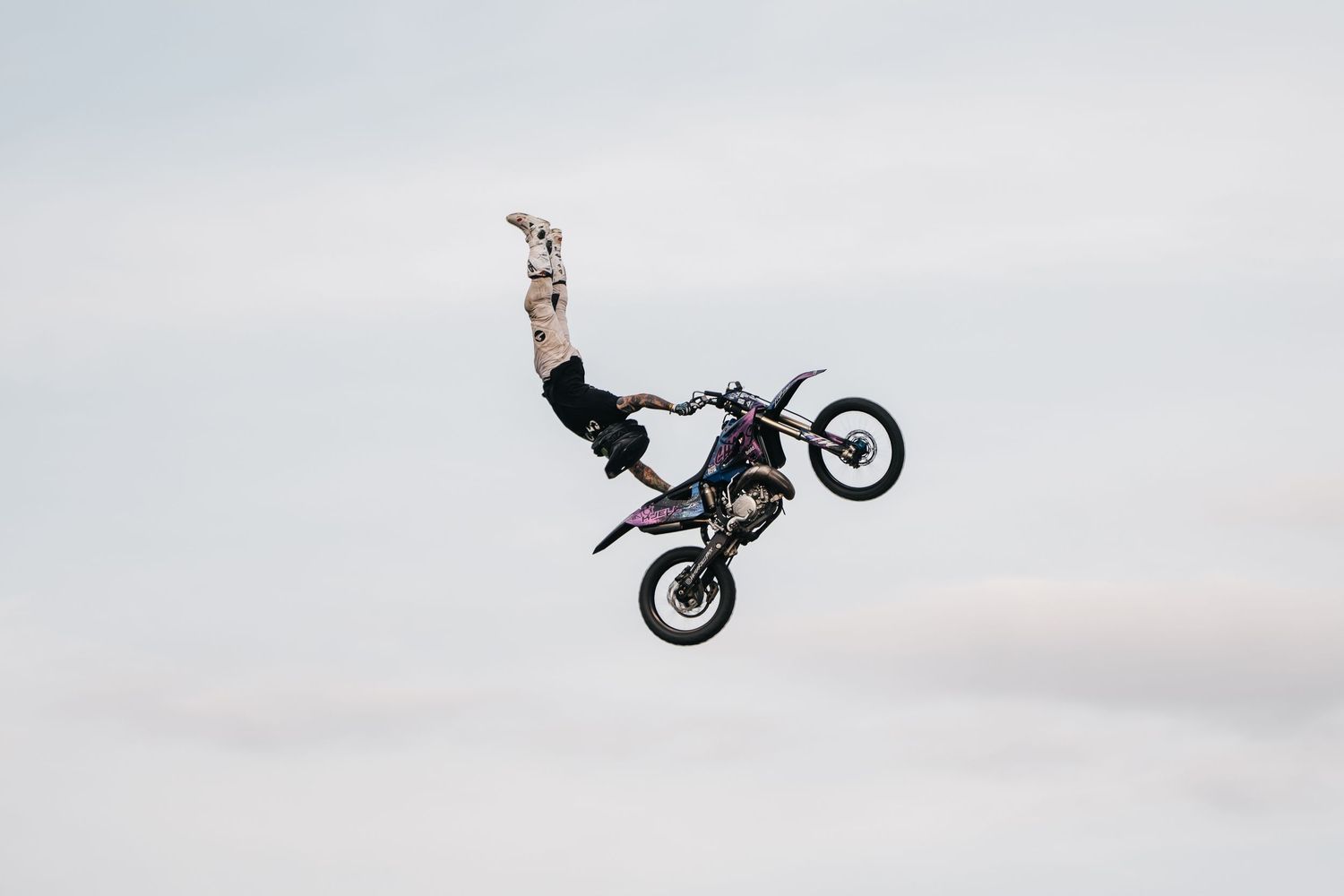 A sequence of motorcycle stunt jumps showing a rider performing aerial tricks against a cloudy sky background.