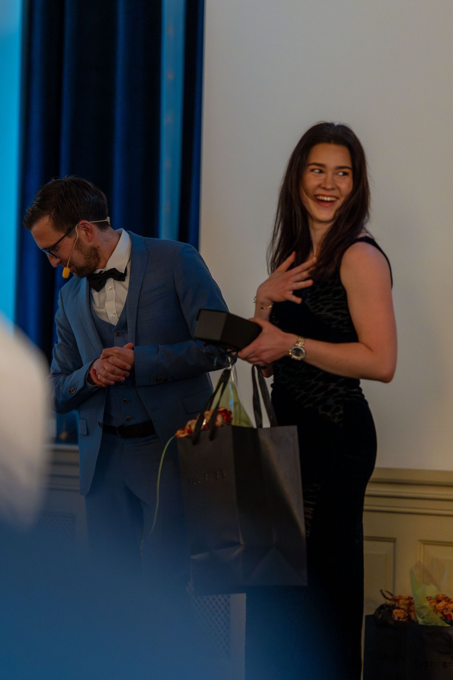 Guests share joyful moments during formal celebration in blue-lit venue.