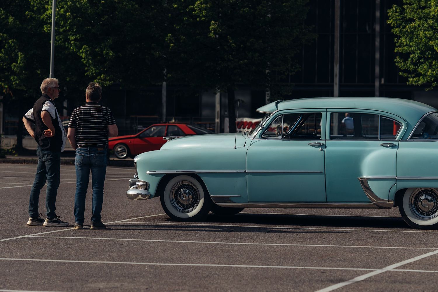 Mint green classic car being admired at an outdoor car show.