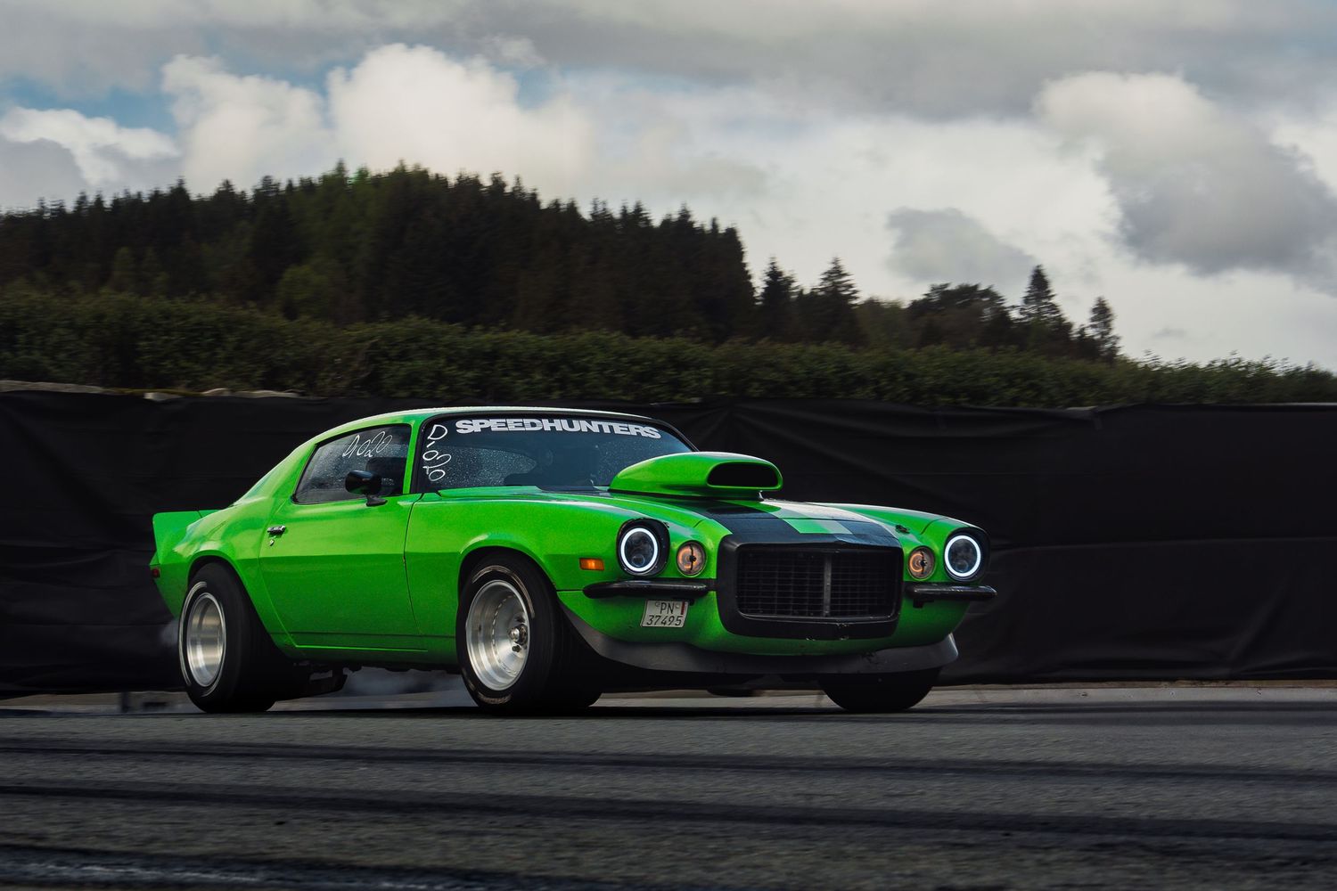 A bright green custom Dodge Challenger muscle car photographed from multiple angles on a cloudy day.