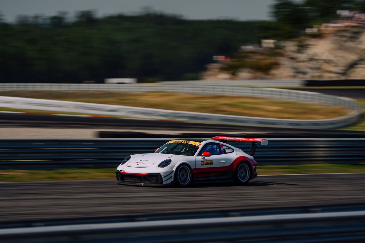 Racing car speeds along a track during a motorsport competition, creating a dynamic motion blur effect.