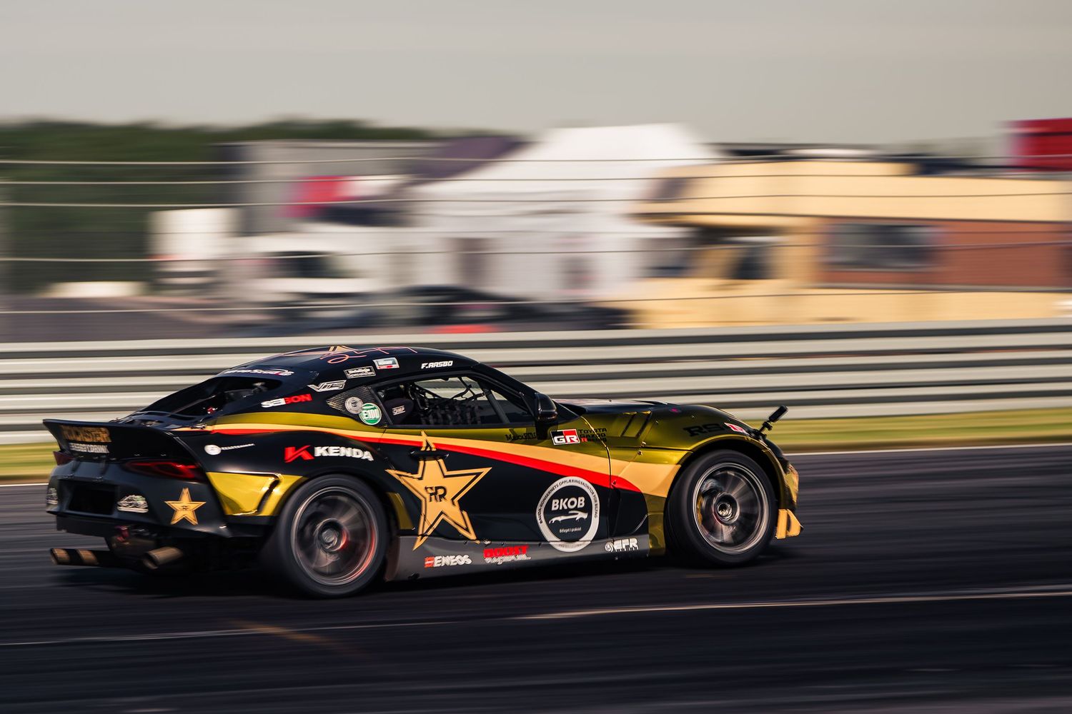 Race cars speed around a track during a motorsport competition, creating a dynamic motion blur effect.