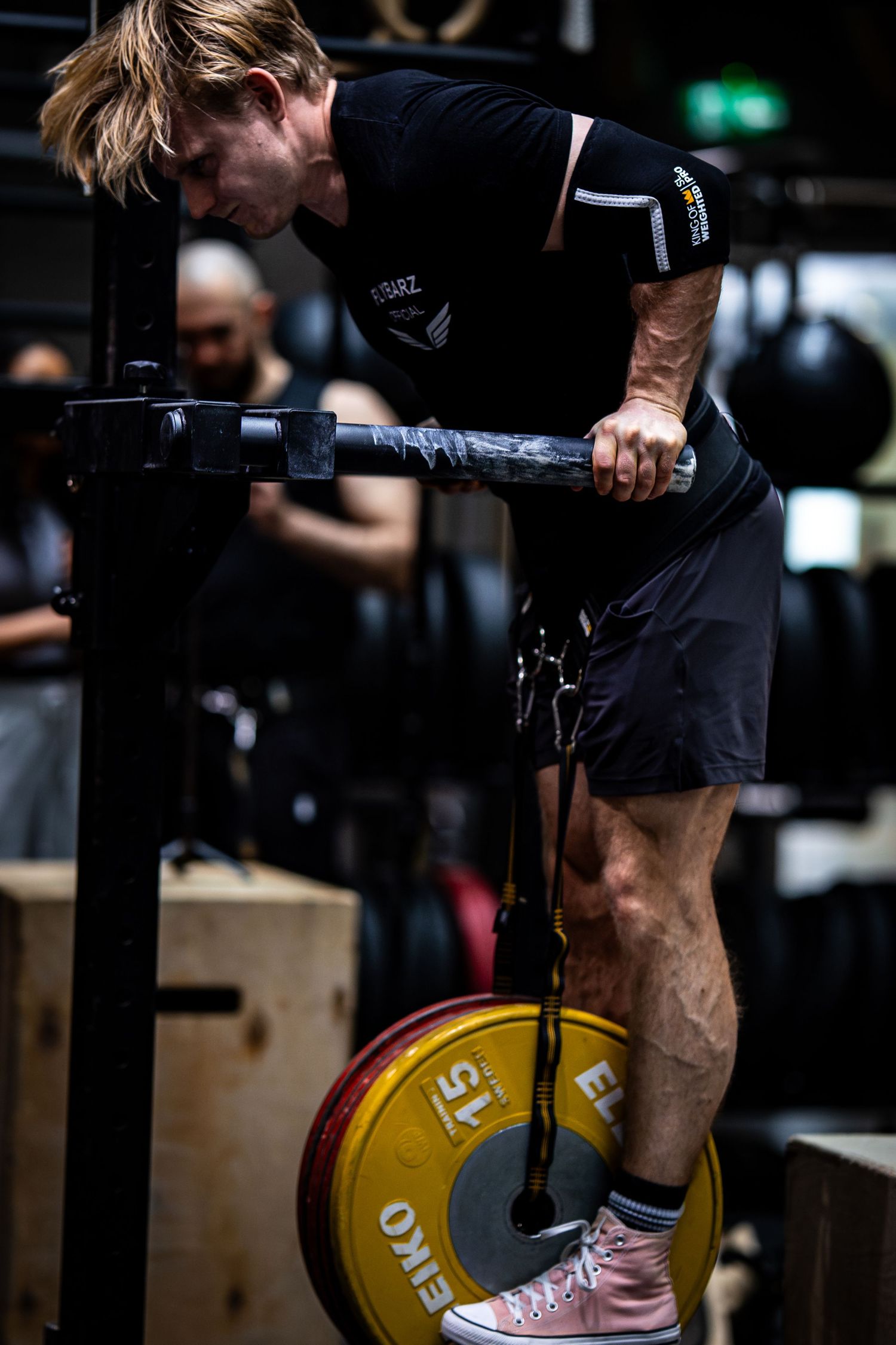 Athlete performing weighted dips with yellow Eleiko plate in dark gym setting.