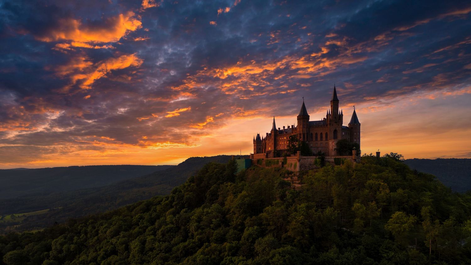 Panoramic view of a stunning castle silhouetted against a colorful sunset sky.