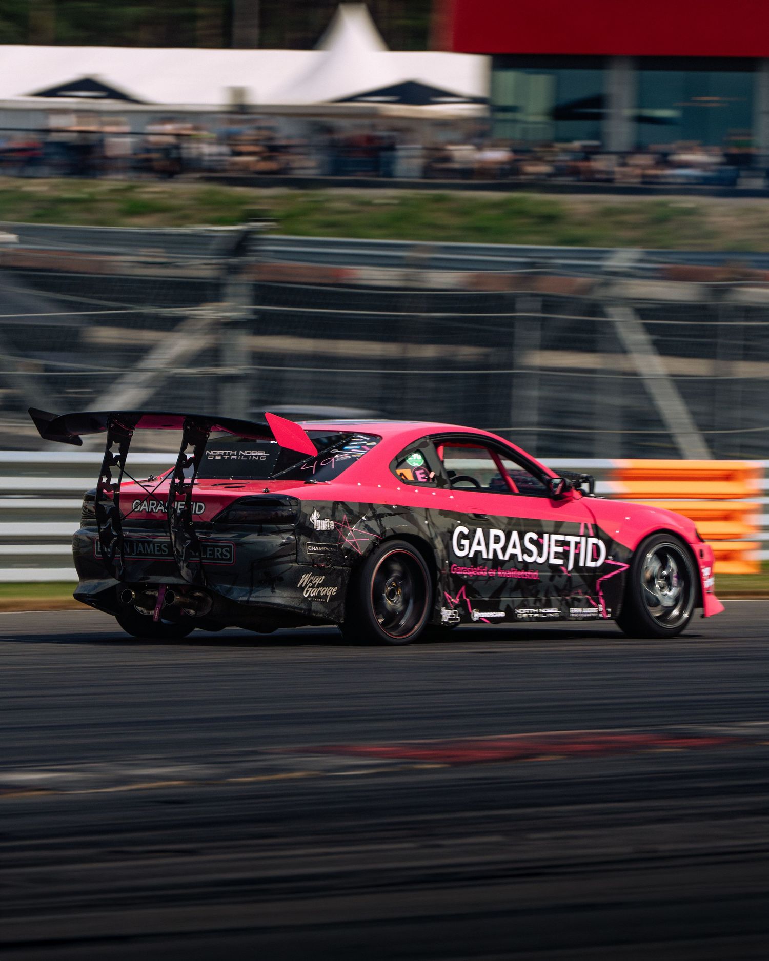 Two drift cars racing side by side on a track with pink and black livery designs leaving tire smoke trails.