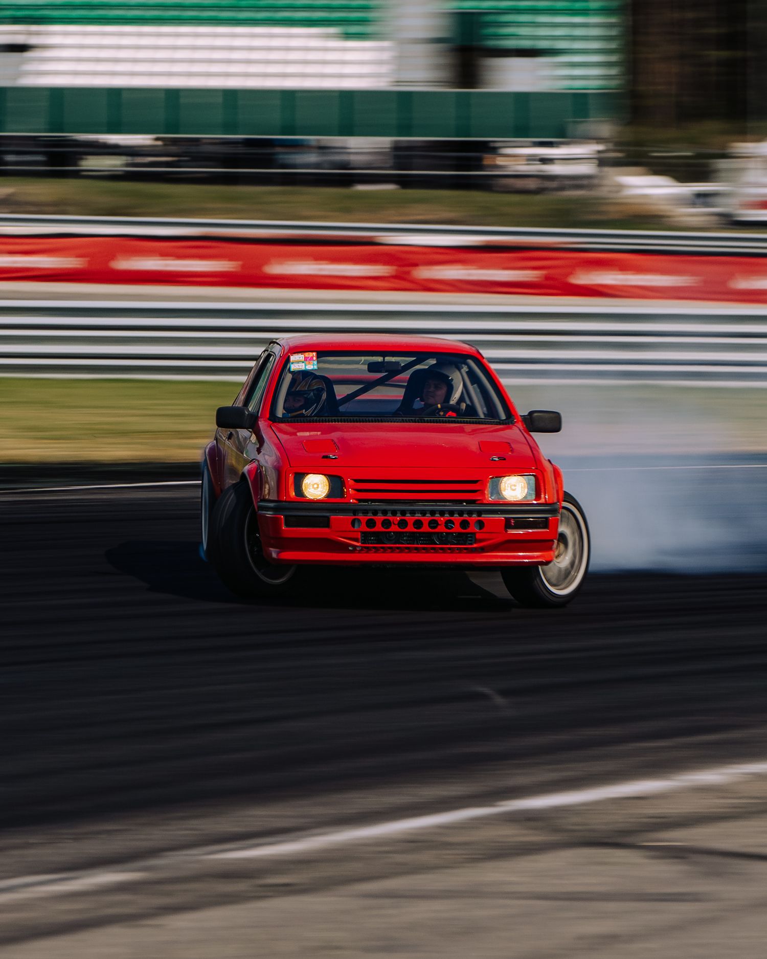 Red sports car racing on a track with motion blur effect showing high-speed movement during competition.